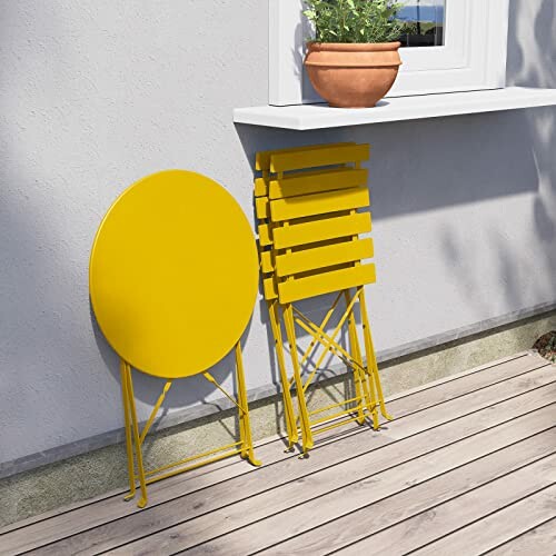 Yellow folding chairs and table leaning against a wall on a patio.